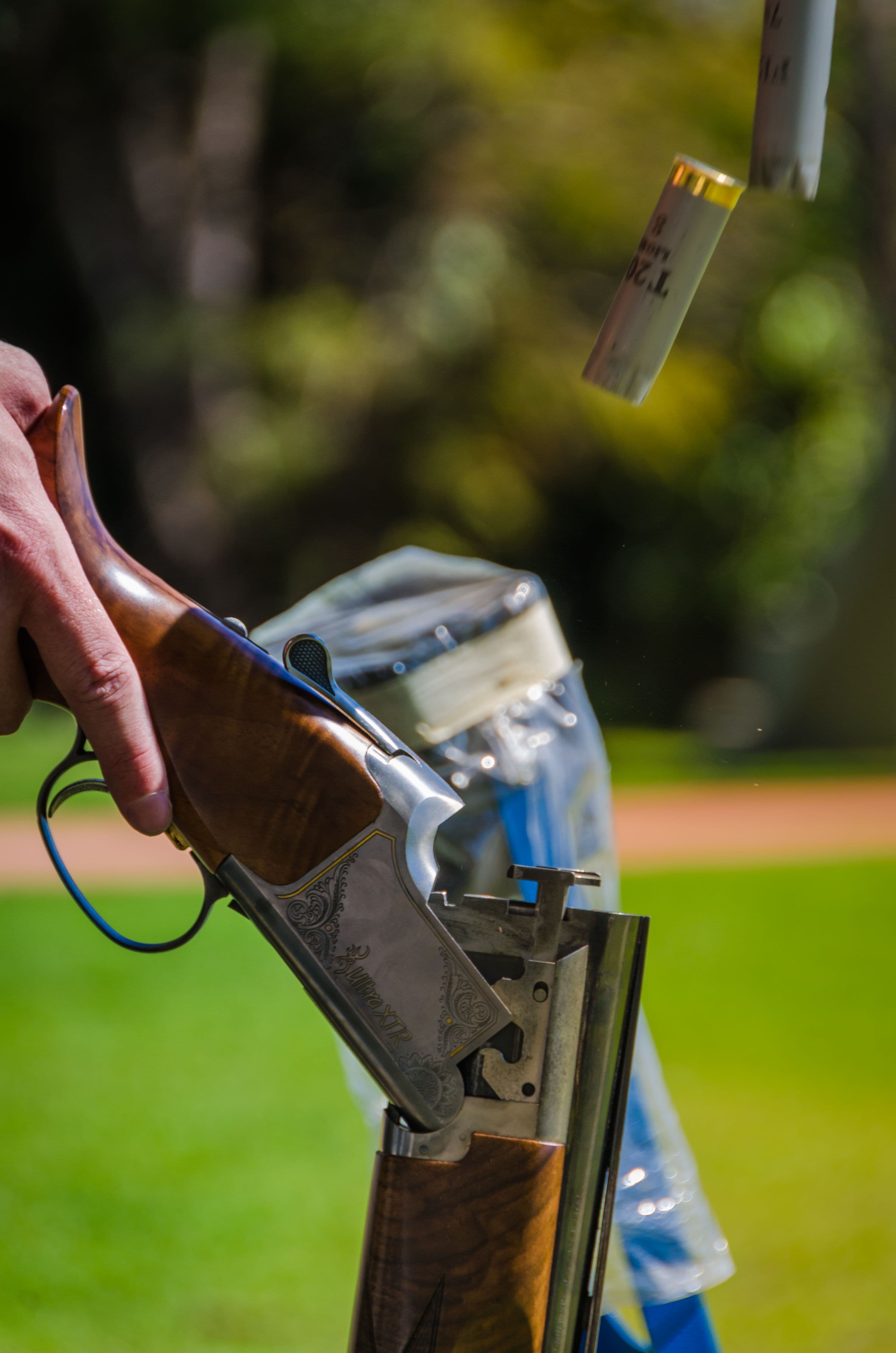 A hand holds an open break-action shotgun as spent shells eject.