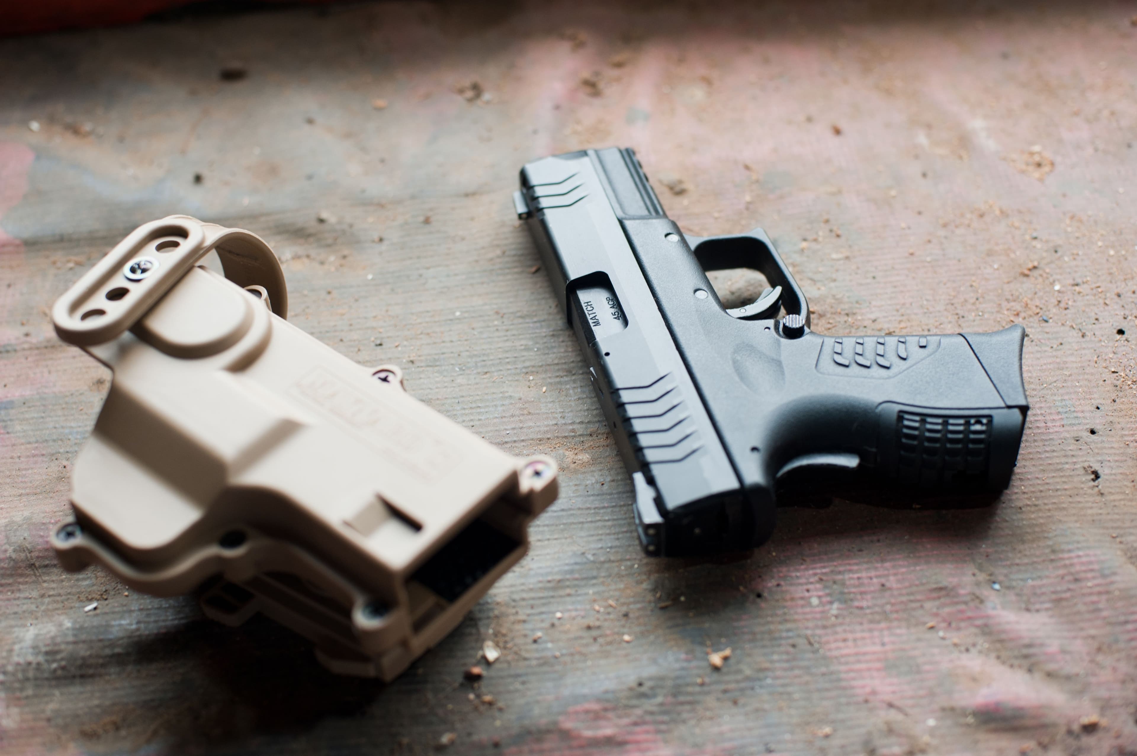Compact pistol resting beside a tan polymer holster.