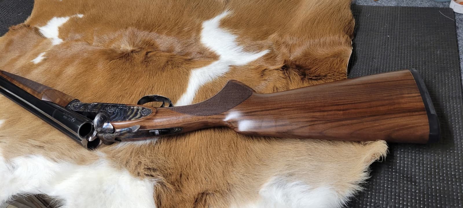 A side-by-side shotgun with an engraved receiver and walnut stock, the coach gun style used in cowboy action shooting