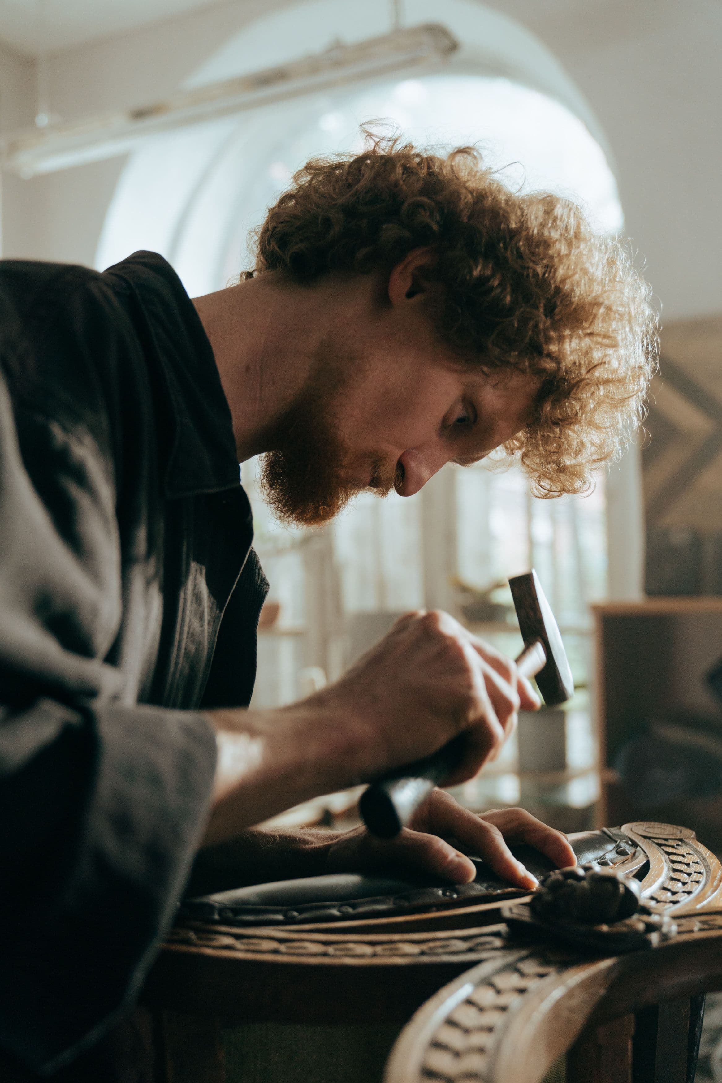 Craftsman using a stamping tool to hand tool a leather piece.