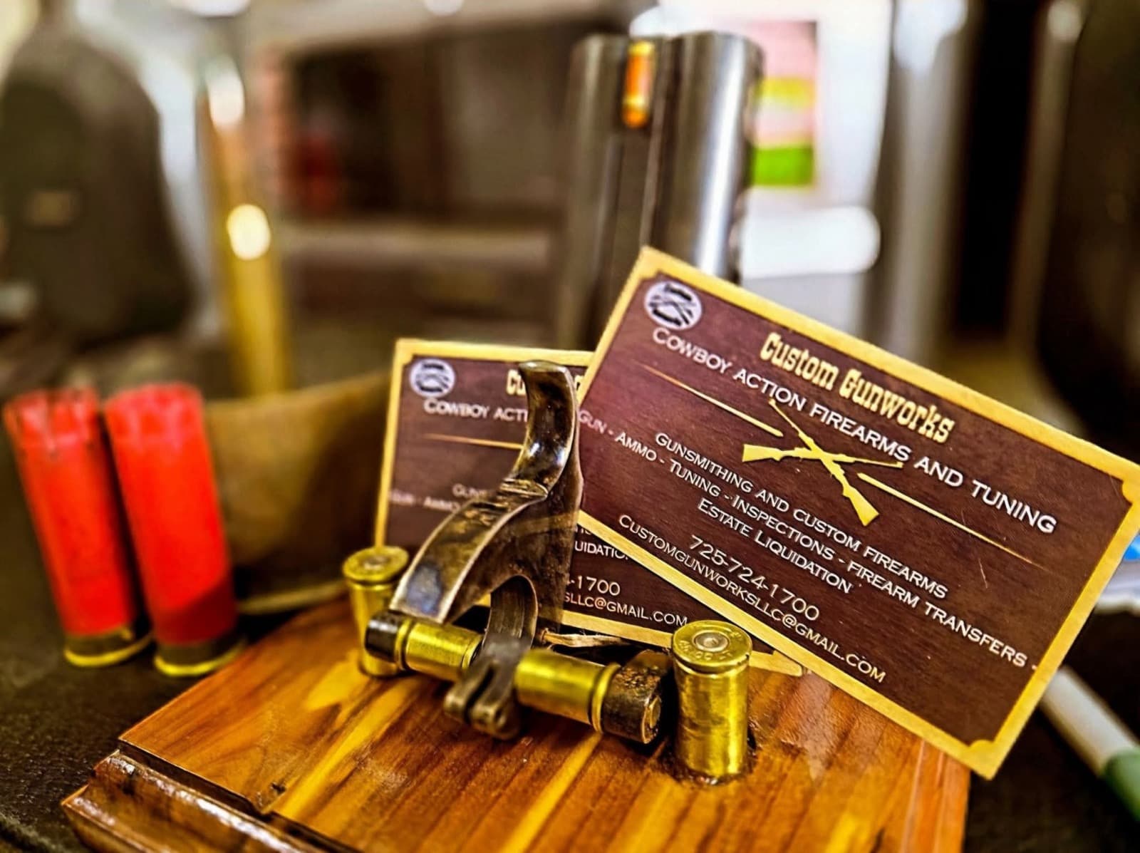 Custom Gunworks business cards listing gunsmithing, tuning, inspections, and firearm transfers, on the shop bench