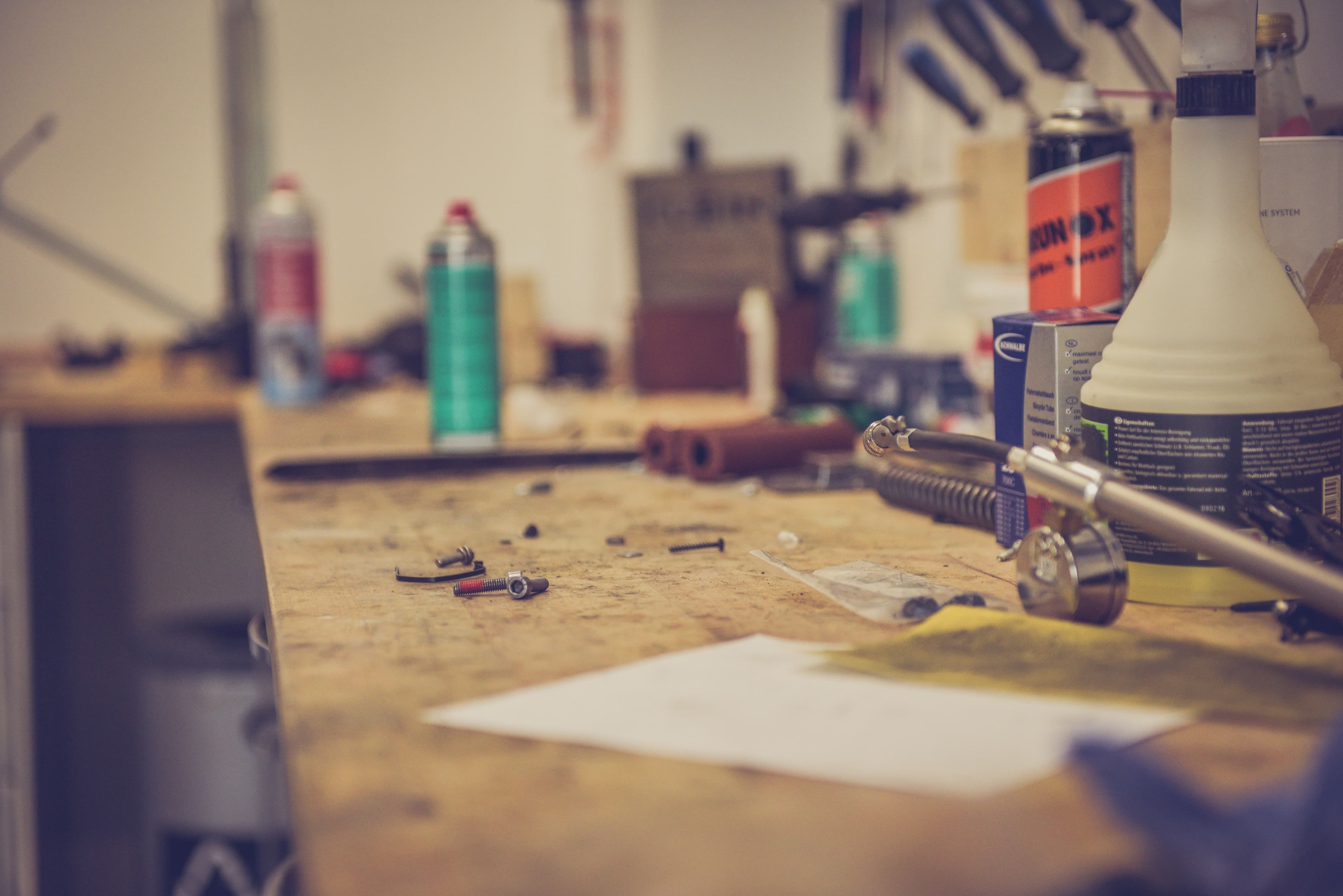 Gunsmith workbench with cleaning solvents, small parts, and hand tools.