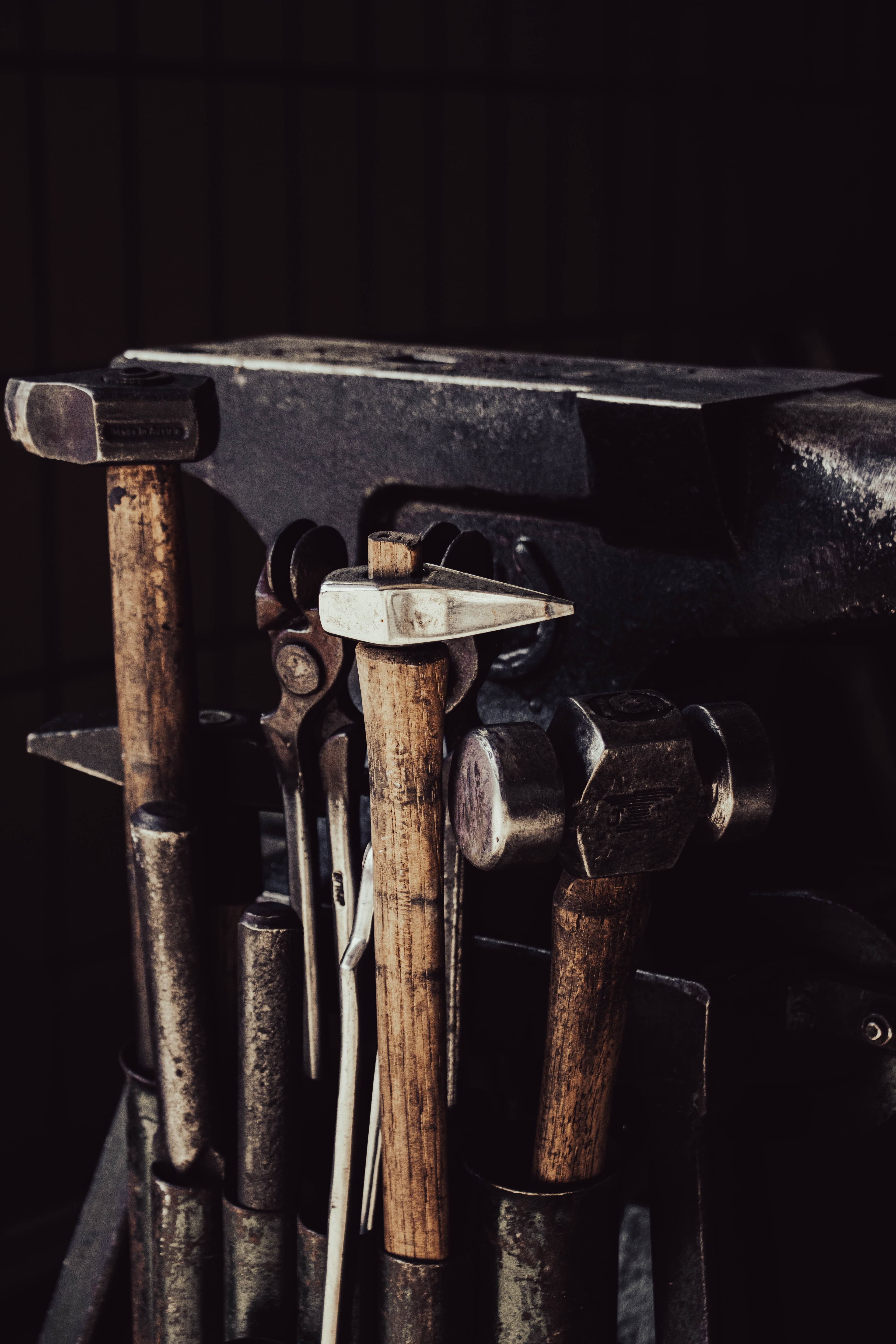 A collection of hammers and hand tools resting on an anvil workbench.