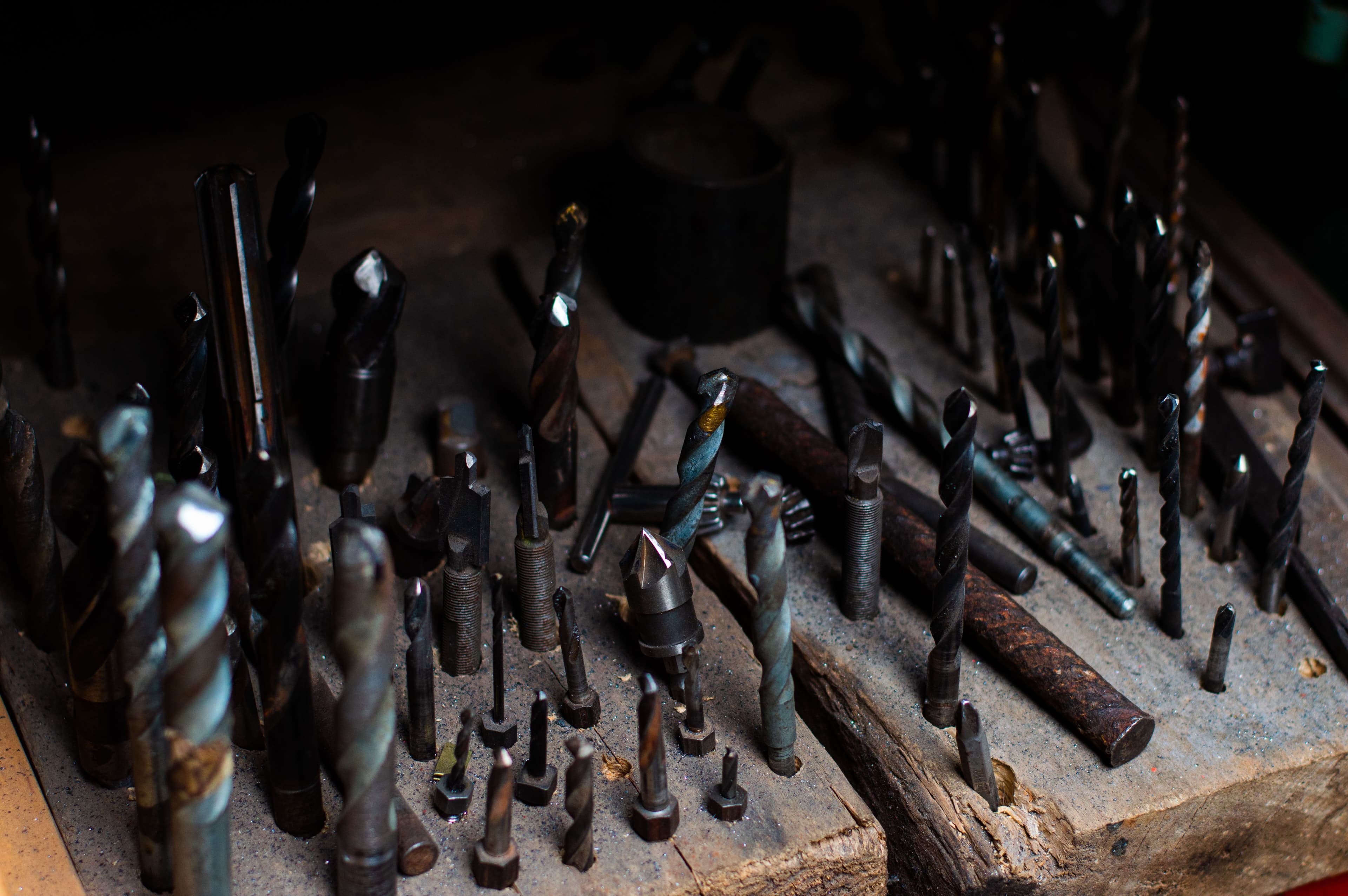 An assortment of drill bits and precision tools standing upright on a workbench.