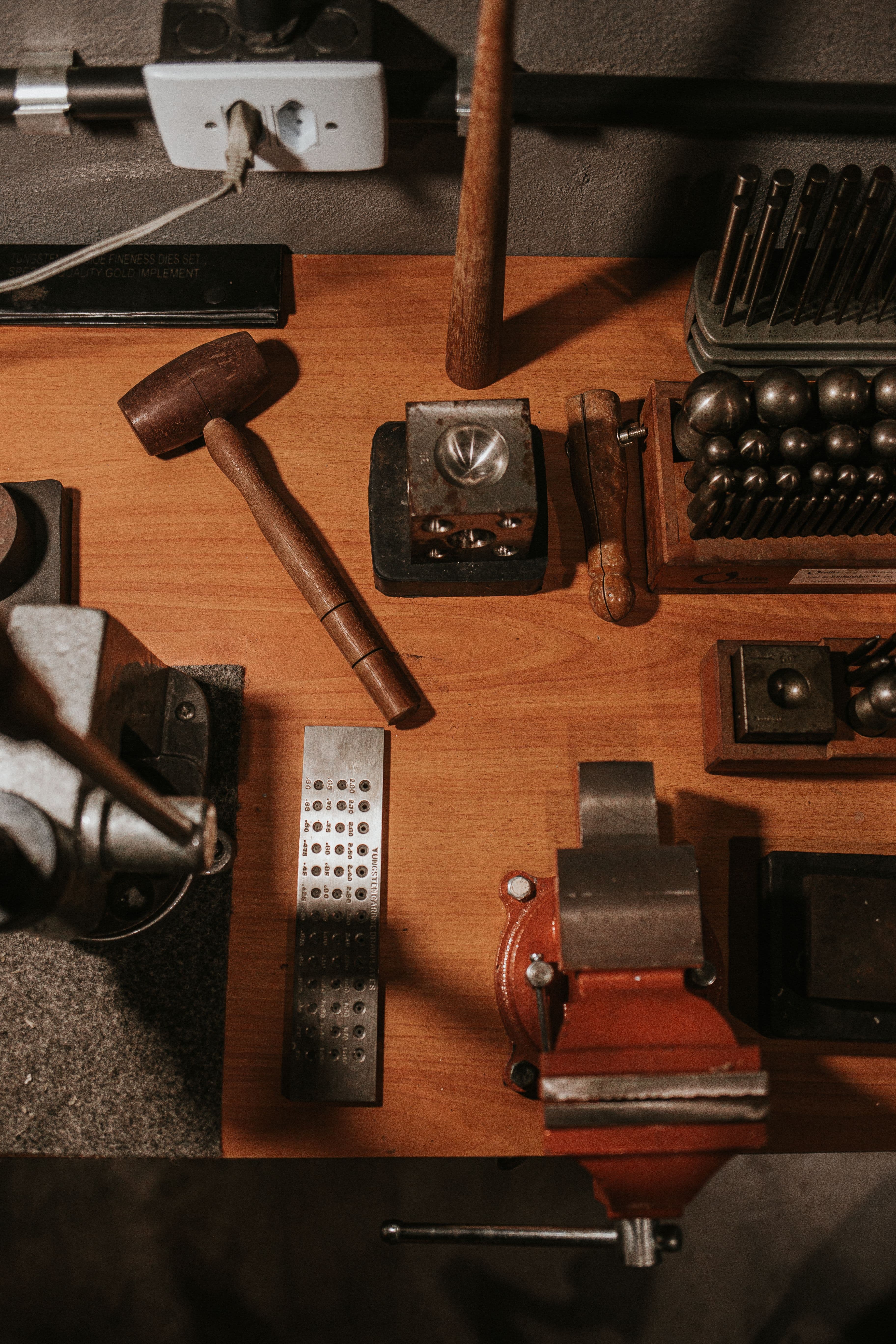 Overhead view of a gunsmith workbench with a punch and die set and vise.
