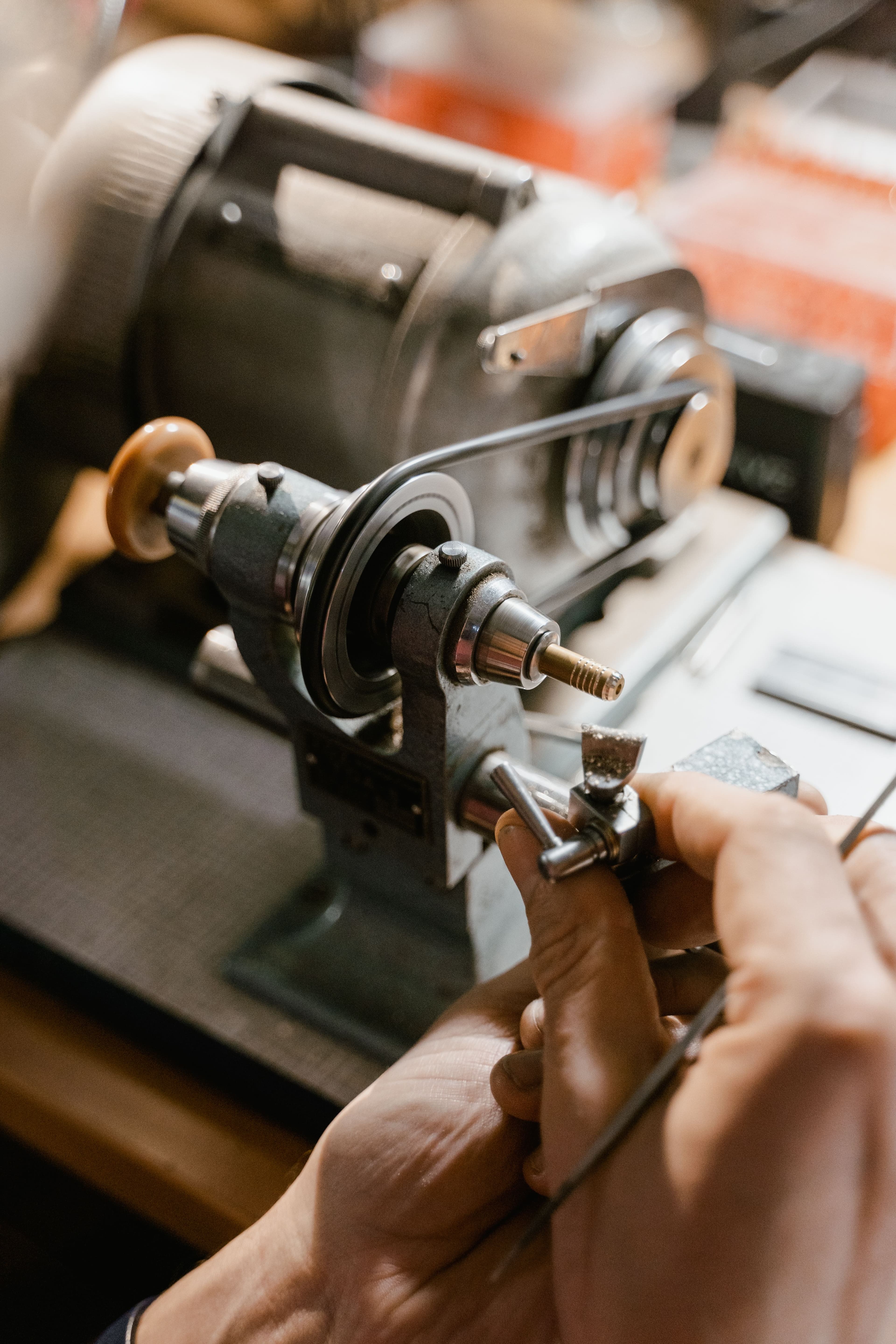 Hands adjust the chuck of a small benchtop lathe.