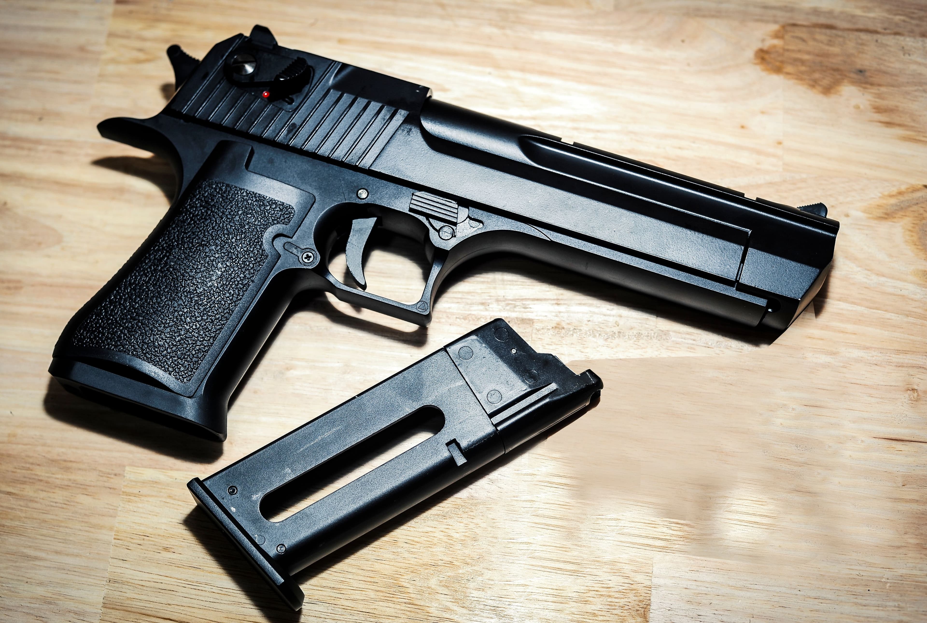 A large-frame semi-automatic pistol disassembled on a wood workbench.