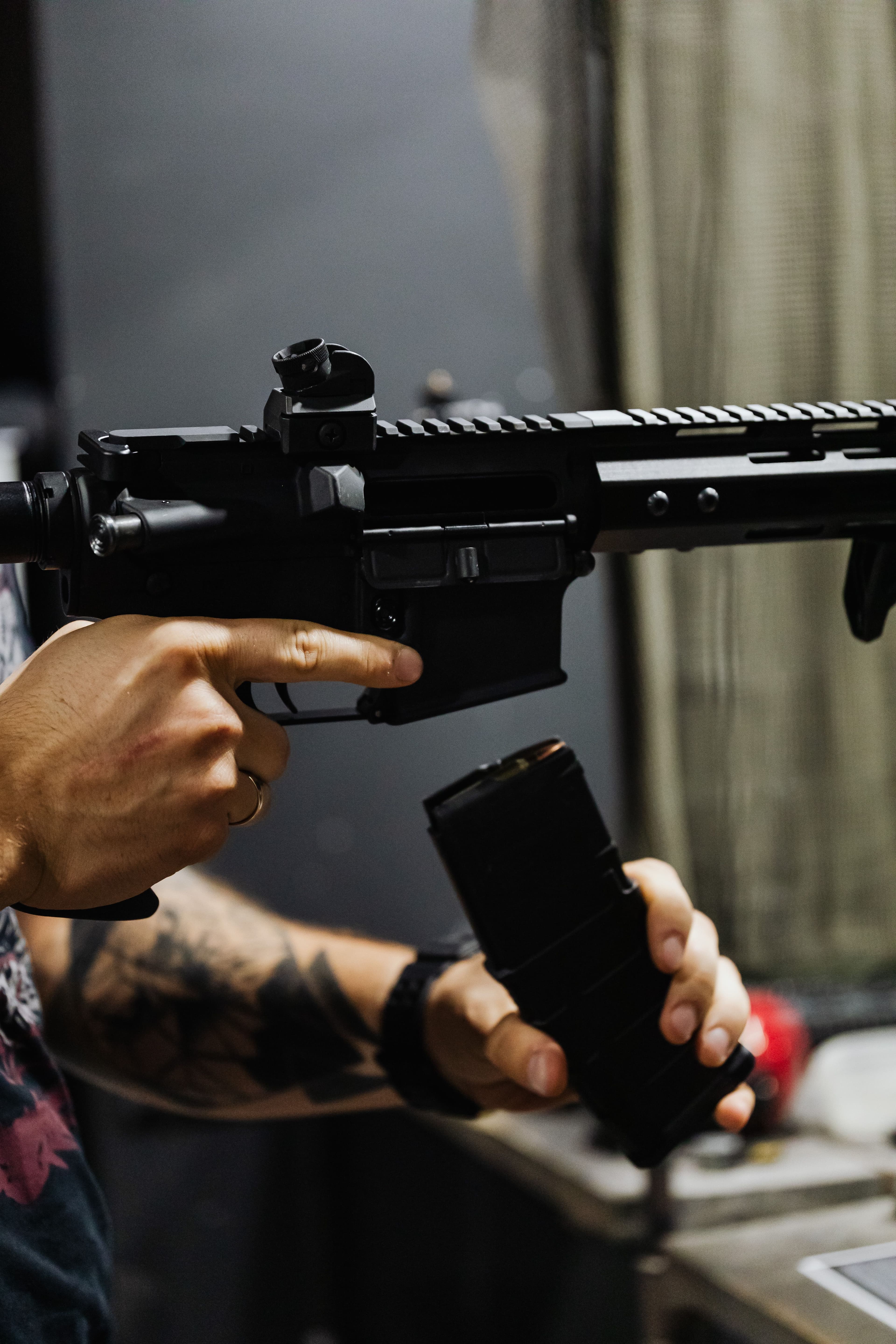 Close-up of hands inserting a magazine into an AR-style rifle.