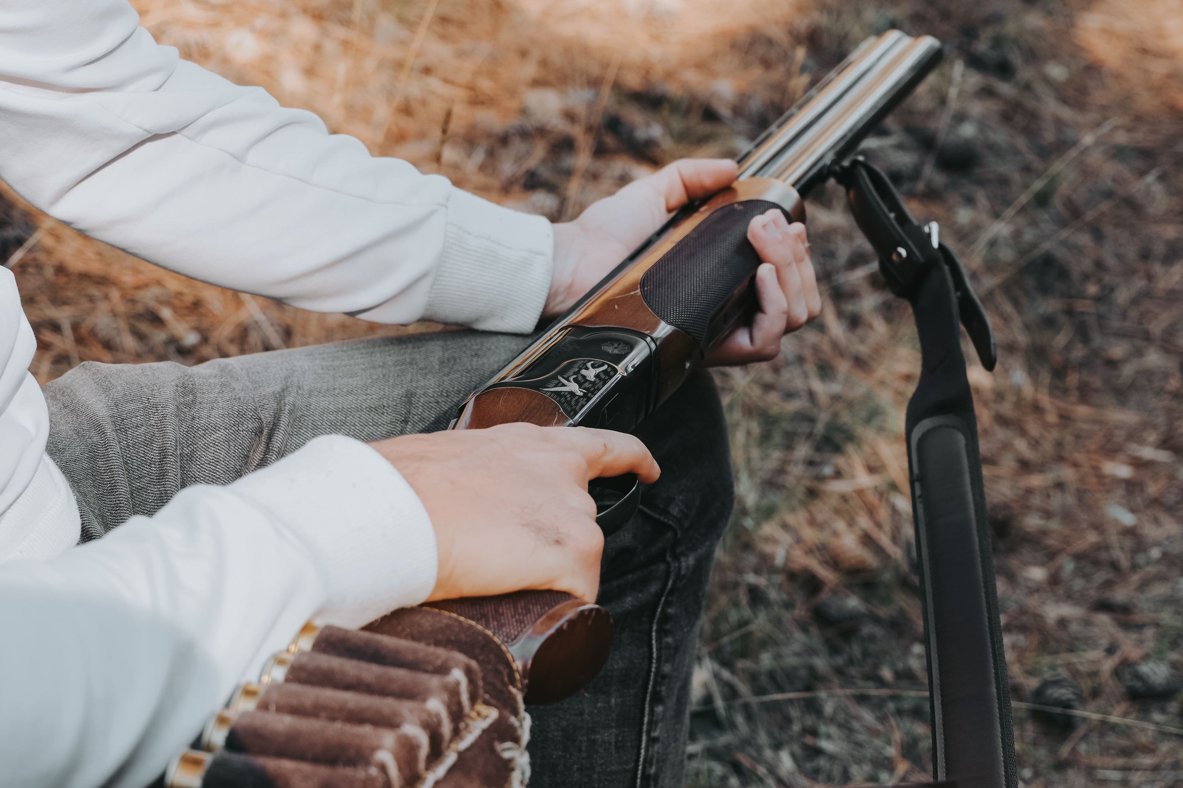 A hunter loads shells into an over-under shotgun outdoors.