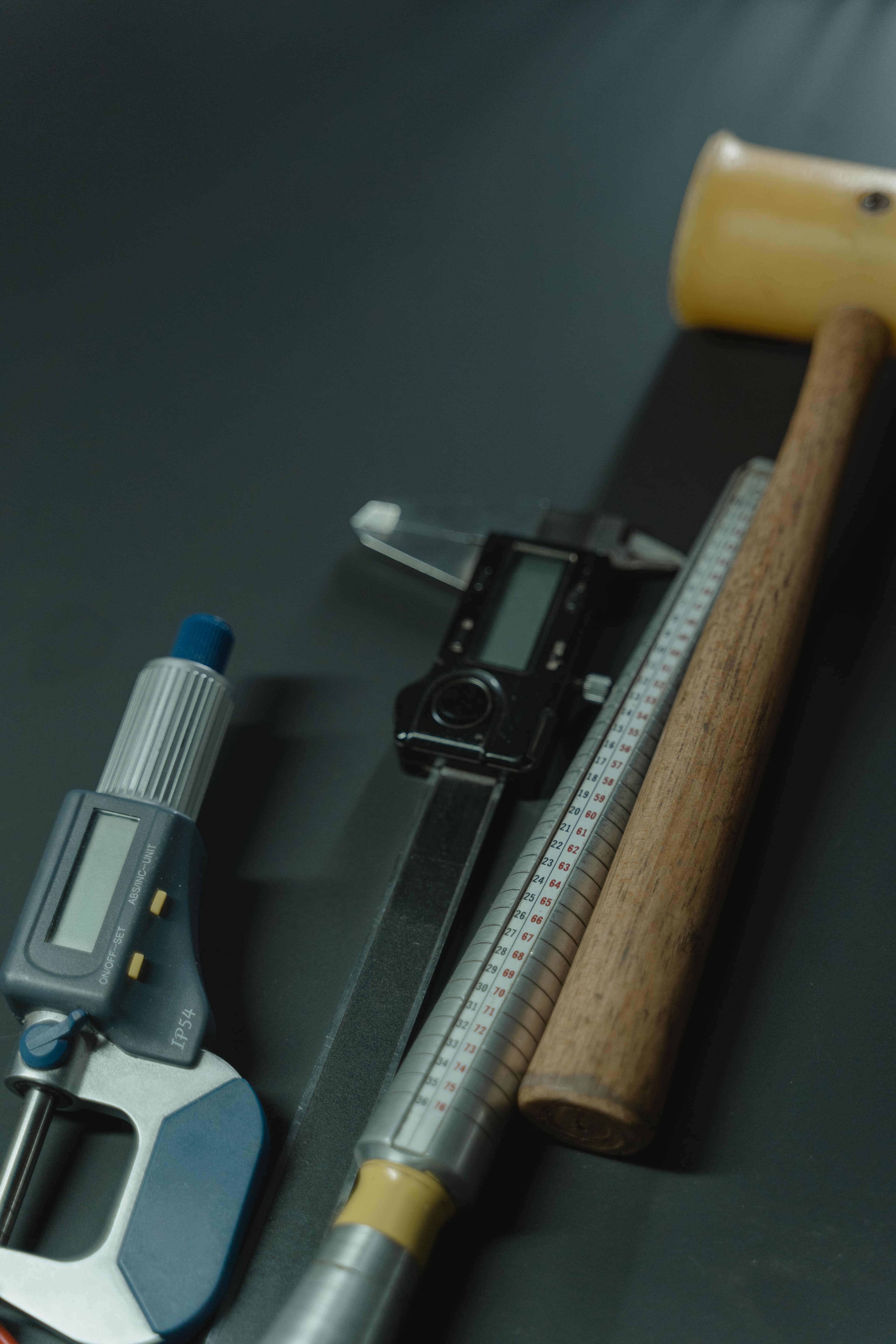 Precision gunsmithing tools including a caliper, micrometer, and wooden mallet.
