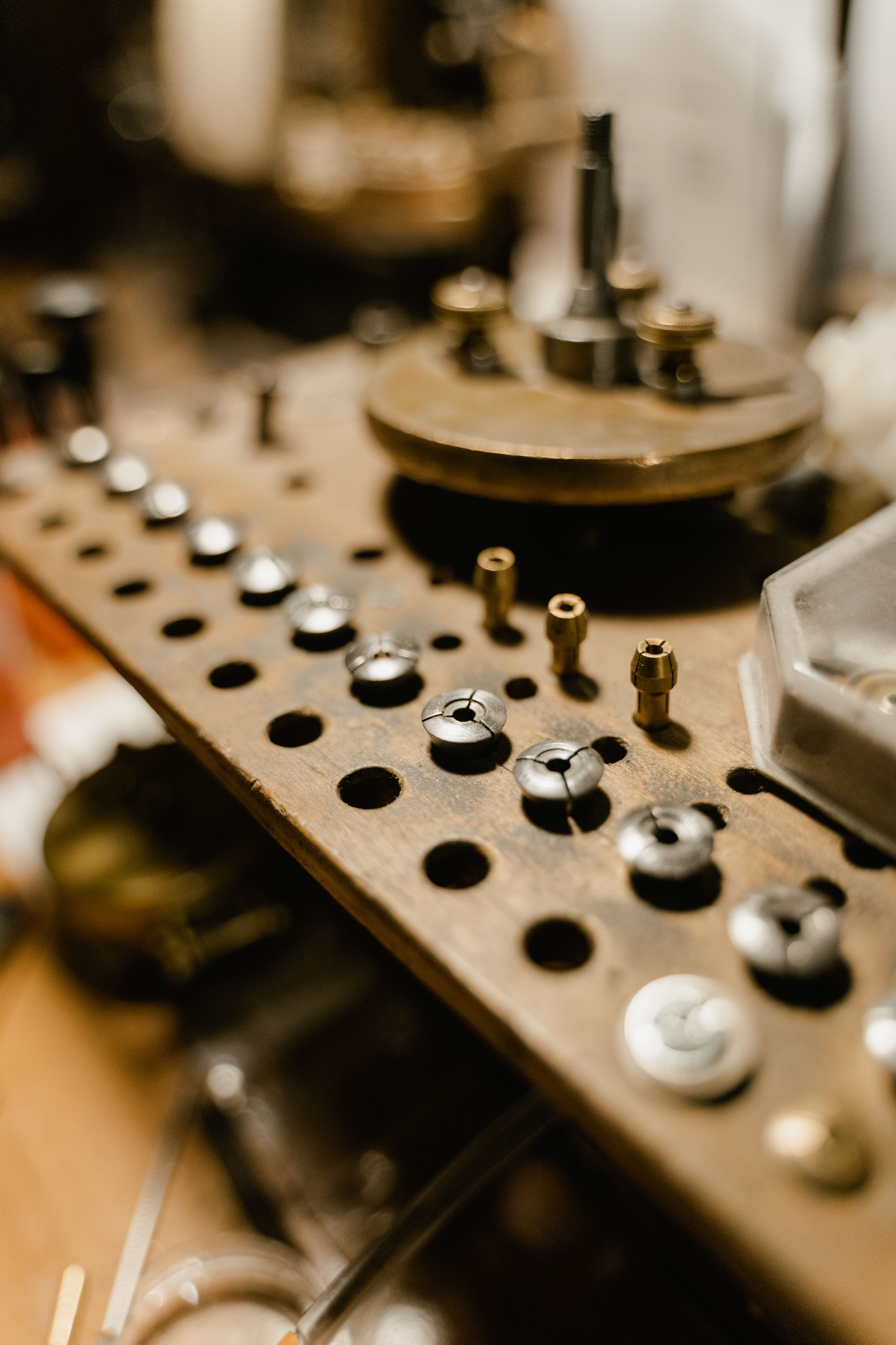 Small precision collets and fittings organized on a workshop pegboard.