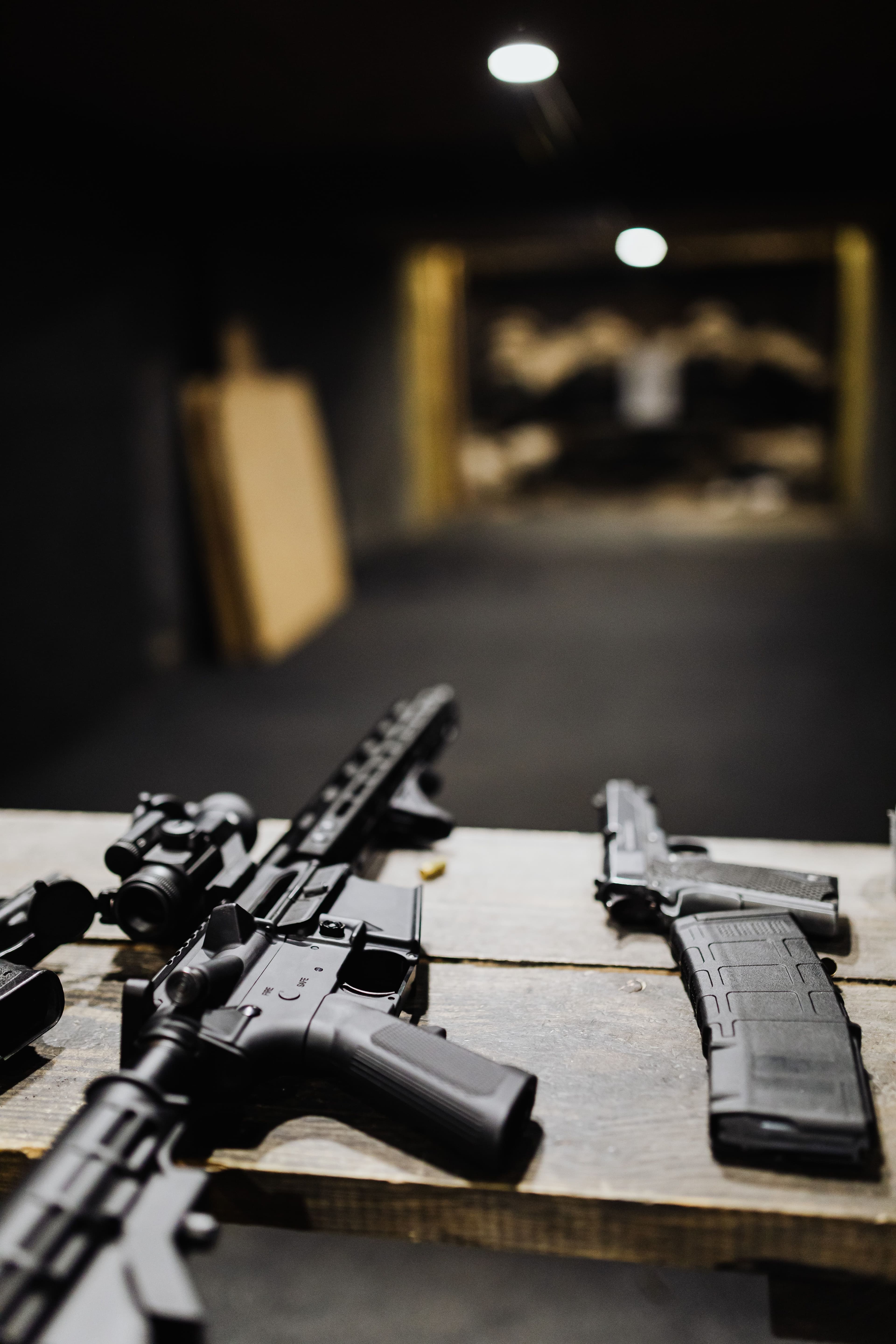 A rifle with scope and a pistol laid side by side on a range bench.