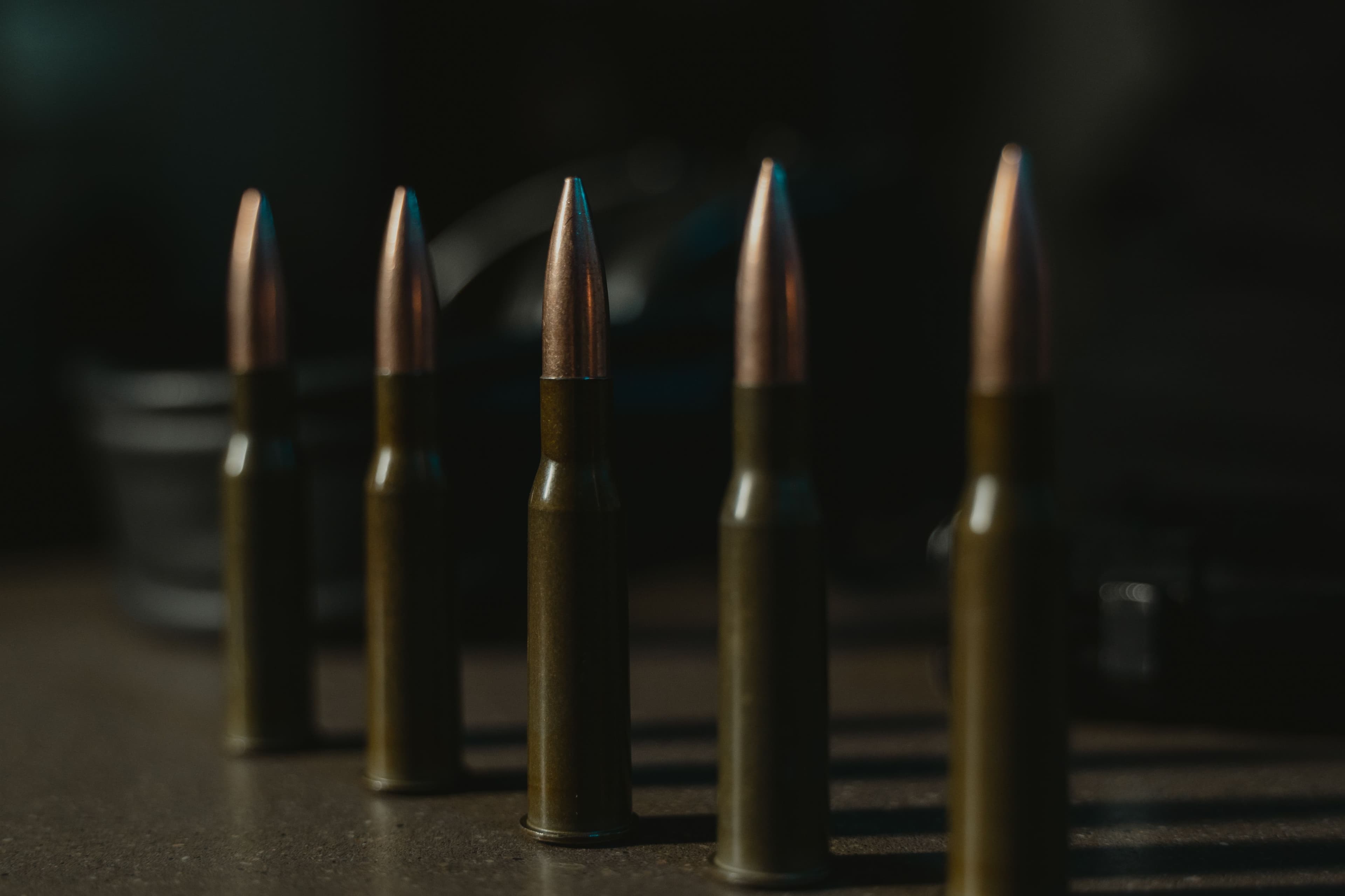 A row of rifle cartridges lit dramatically against a dark background.