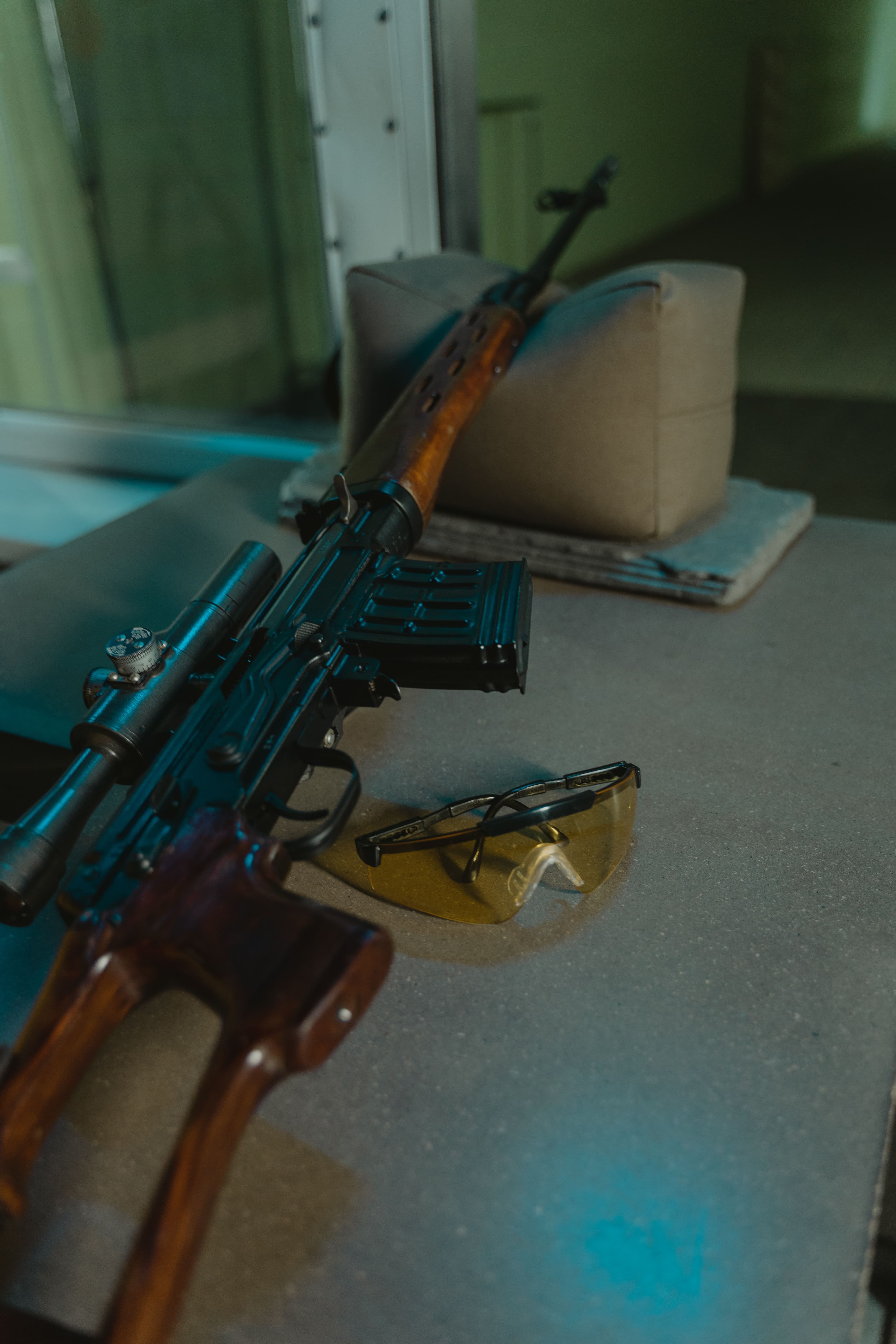 Close-up of a scoped rifle resting on a shooting bench rest.