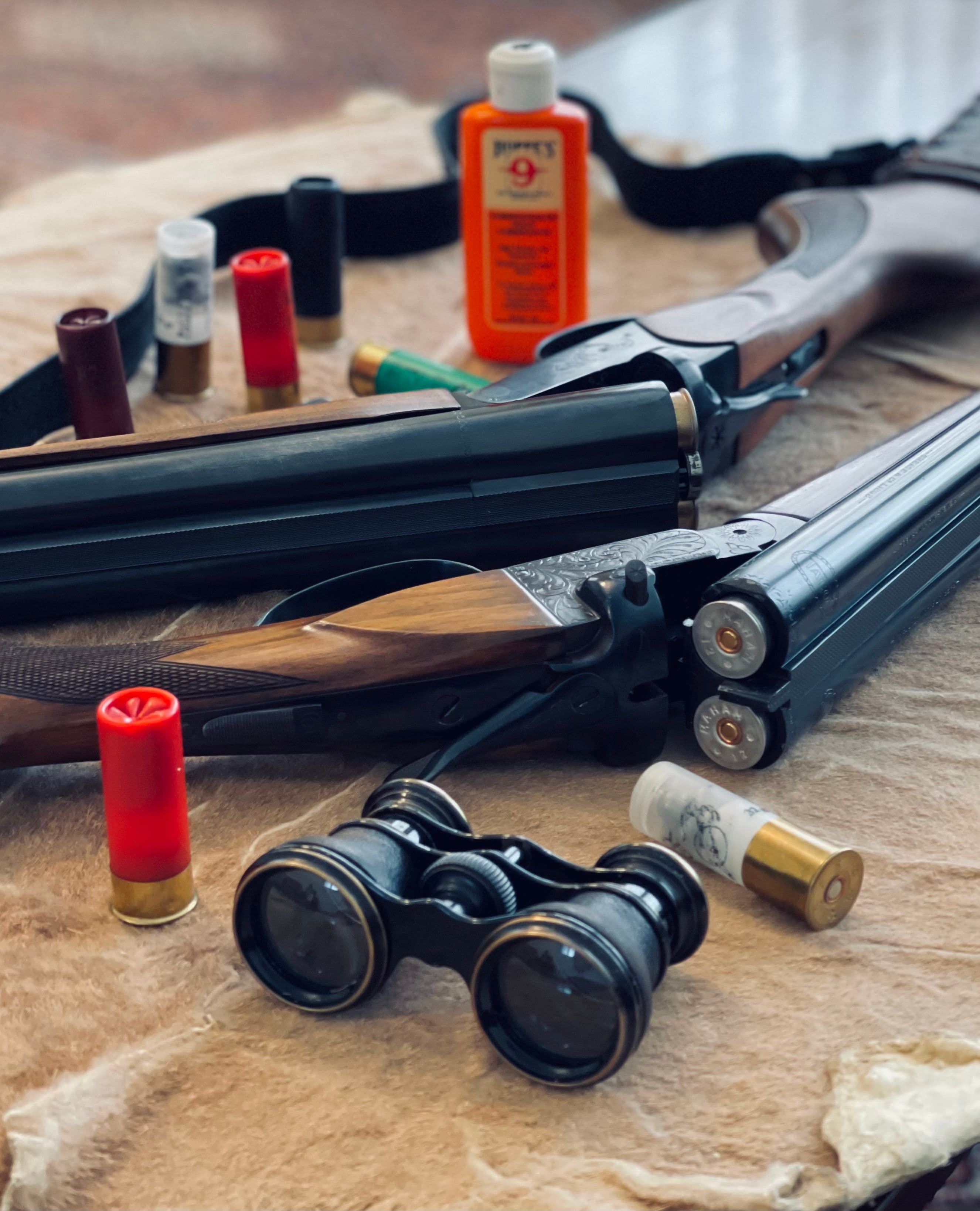 A double-barrel shotgun with shells and gun cleaning oil.