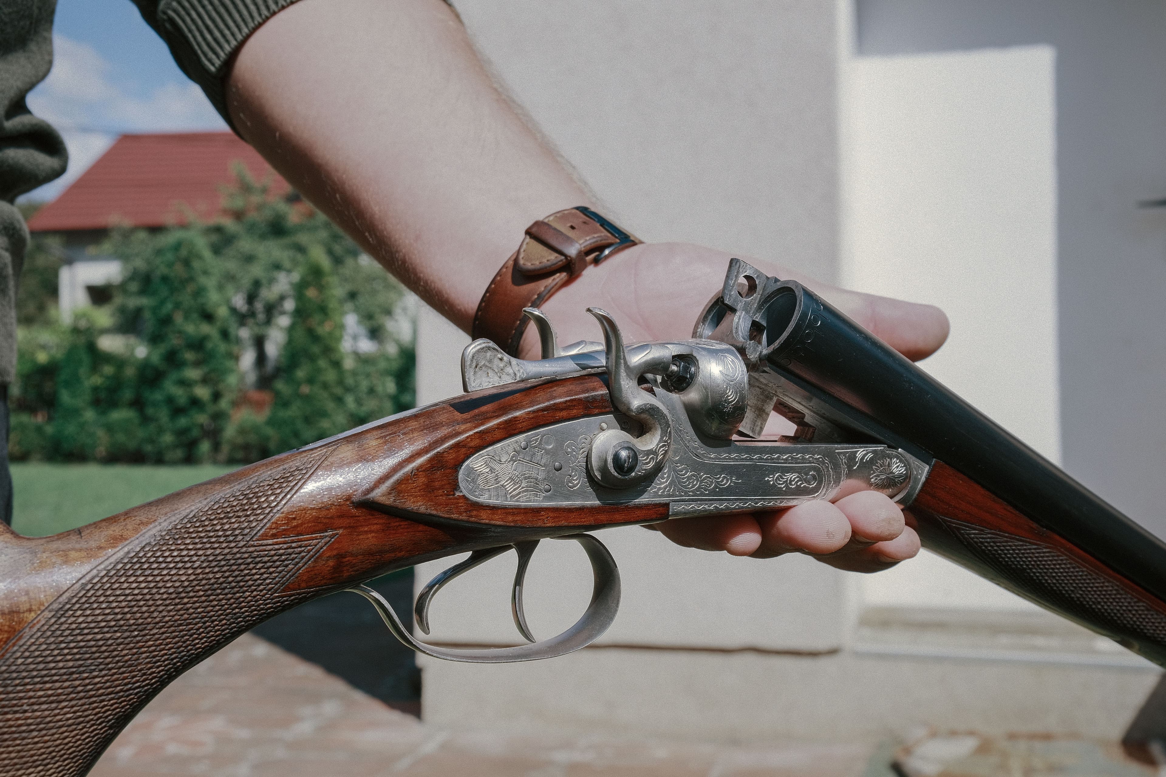 Hands hold an open side-by-side double-barrel shotgun.