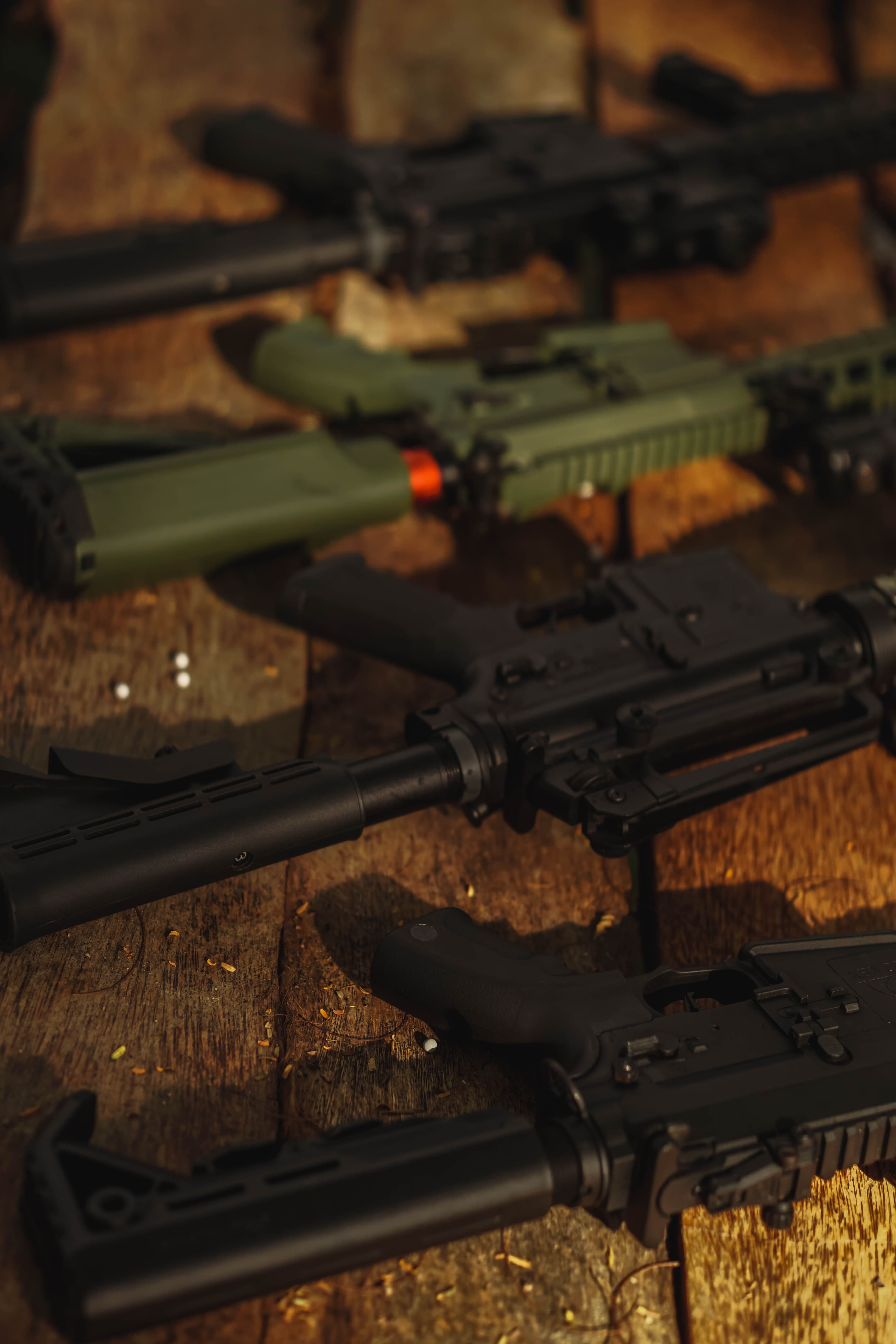 Angled close-up of AR-style rifles fitted with red dot optics.