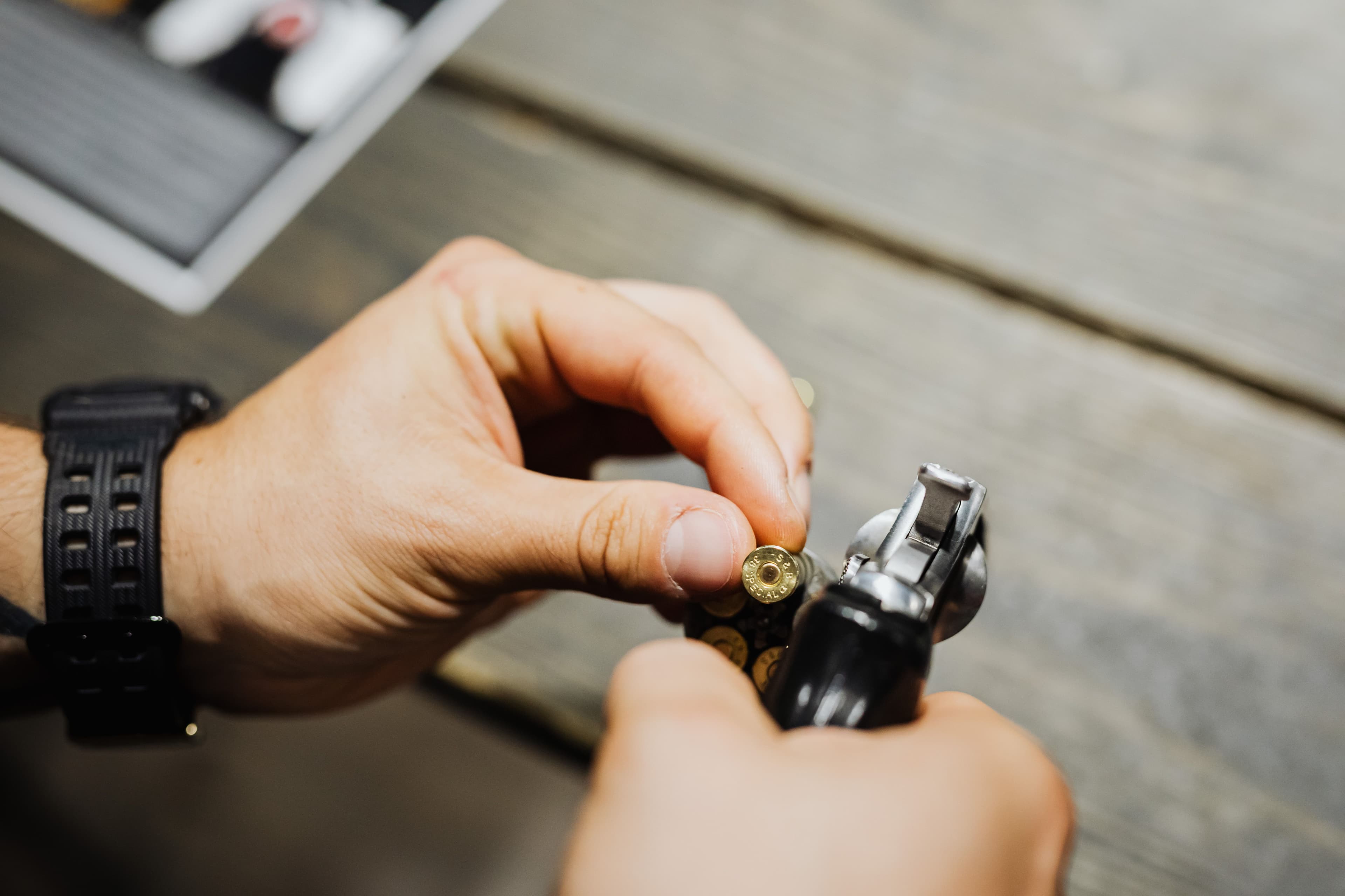 Close-up of hands loading cartridges into a revolver cylinder.