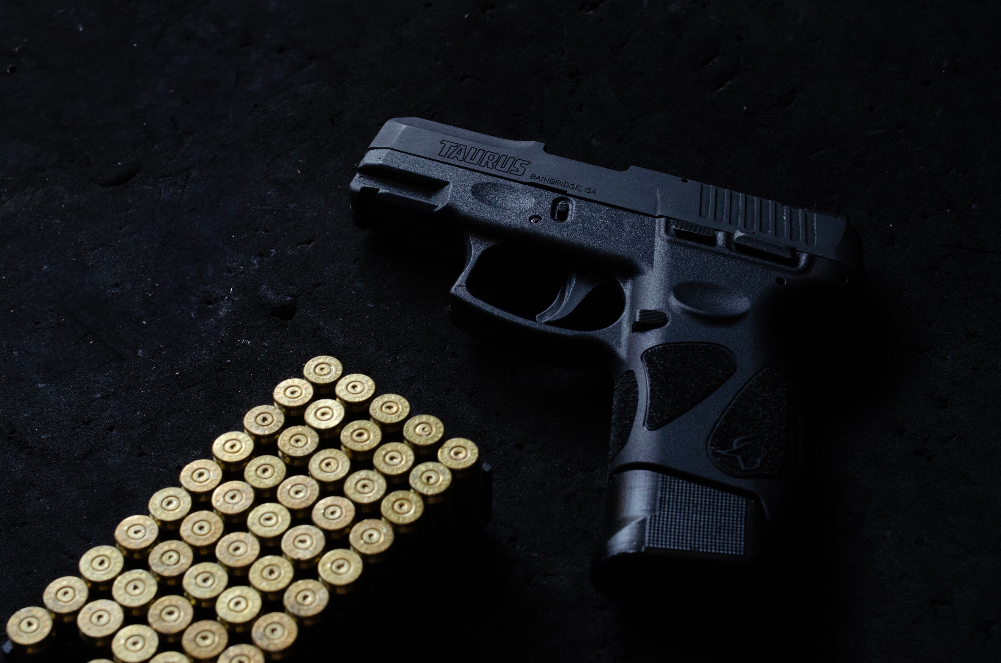 A pistol beside neatly stacked ammunition under dramatic lighting.