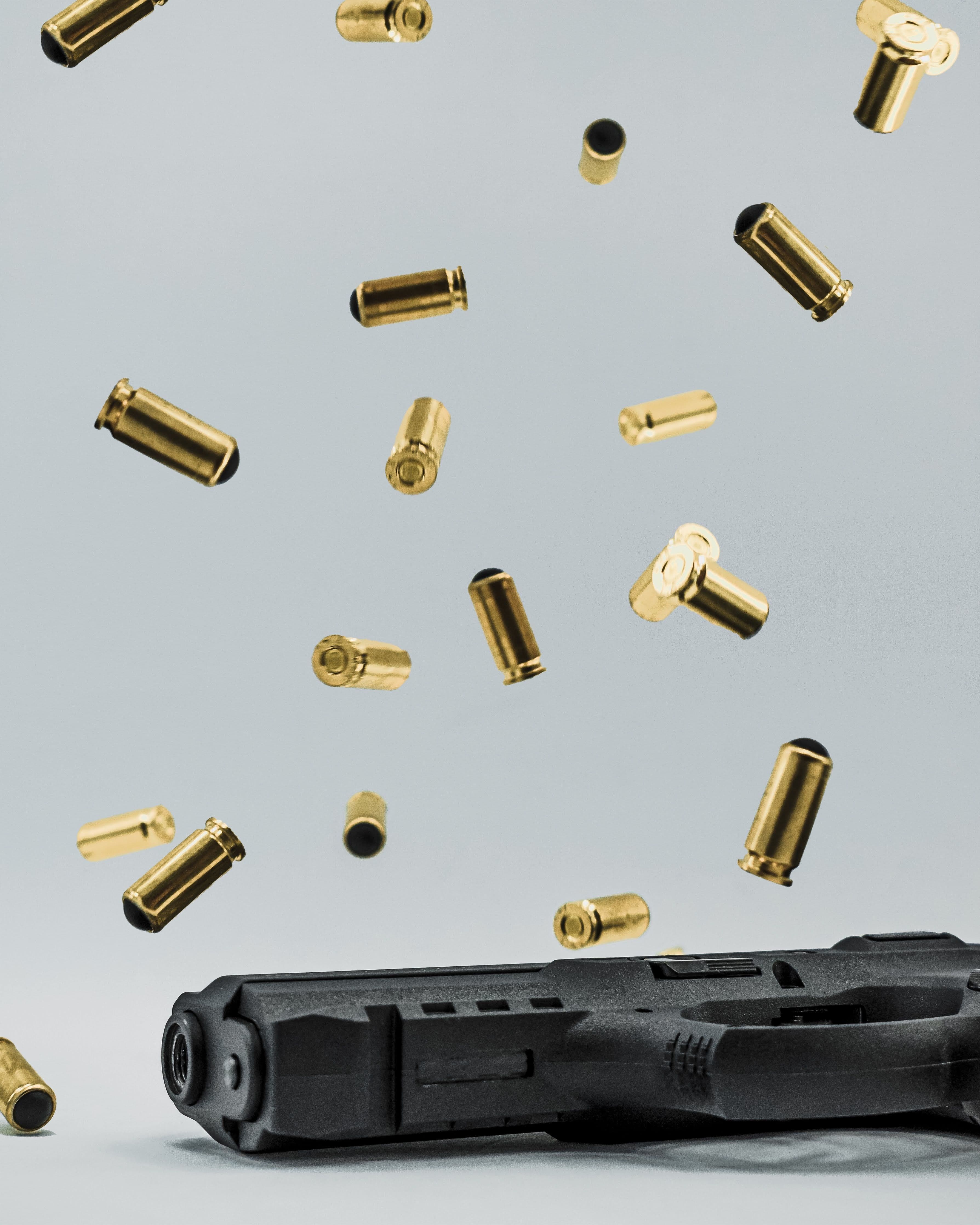 Dramatic studio shot of a handgun with bullets suspended in mid-air.